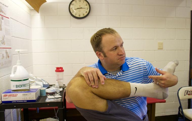 Scott Hooker, head athletic trainer, stretches out soccer player Michael Sass, a senior exercise science major. Photo by Isaac Williams/The Shield